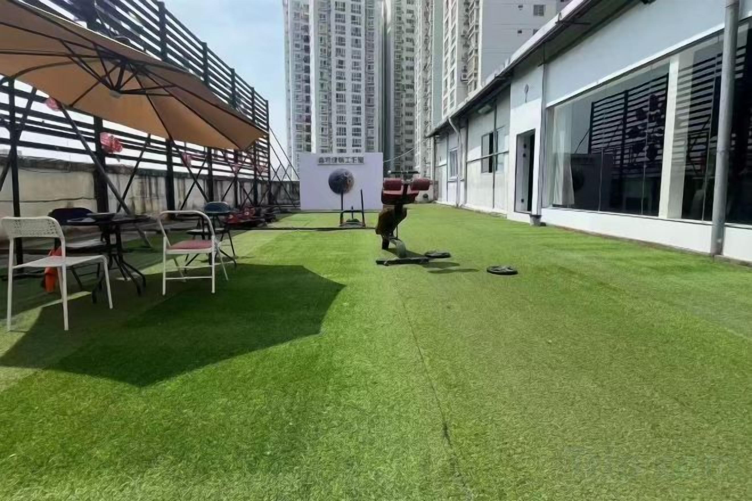 Een dakterras met kunstgras, zitplaatsen en uitzicht op hoge gebouwen.