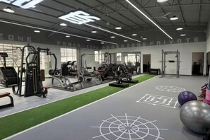A gym with various exercise equipment, a green turf area, and a wall with 'POWER ZONE' text. - Chuanyu Huisen Hotel (Baise)