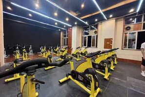 Een sportschool met meerdere spinningfietsen en loopbanden, netjes opgesteld in rijen.