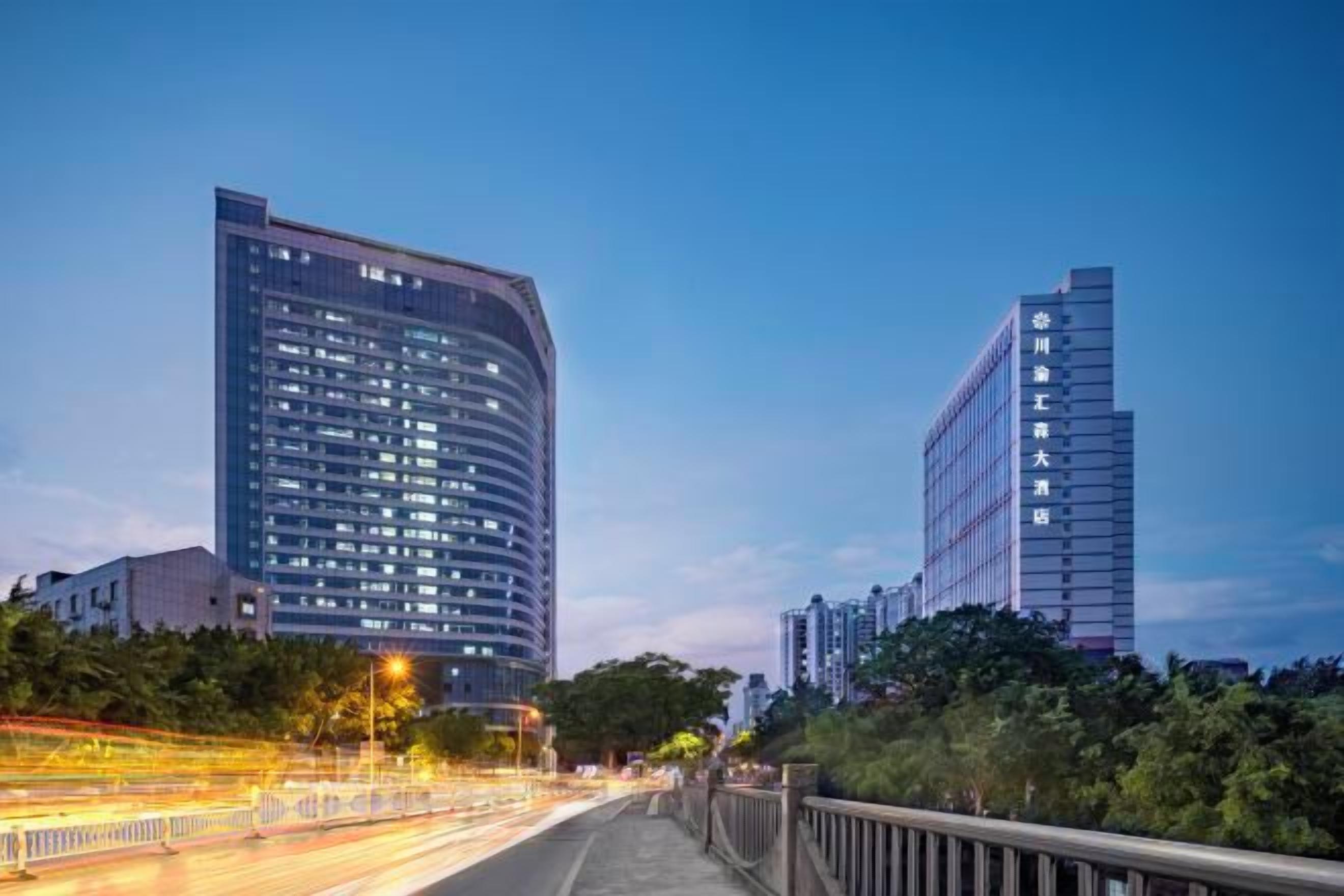 A modern urban street with high-rise buildings, a pedestrian walkway, and a clear sky.