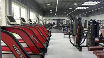 A gym with treadmills, weight machines, and a mirrored wall.