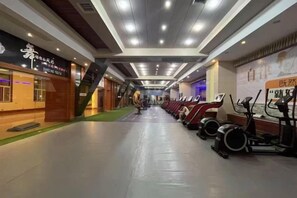 A corridor with exercise equipment, a staircase, and a shop on the left. - Chuanyu Huisen Hotel (Baise)
