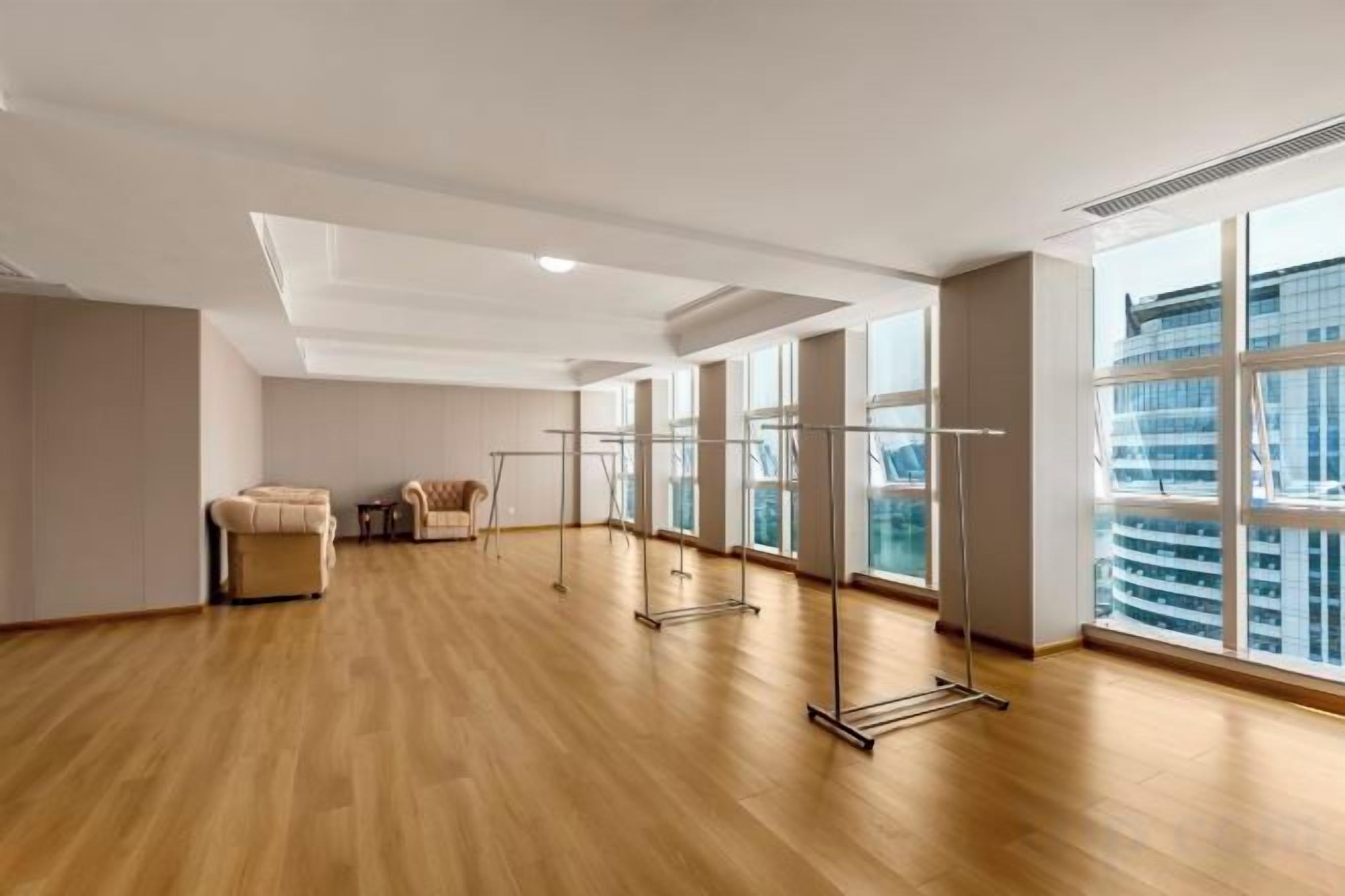 Une pièce spacieuse dotée d’un plancher en bois, de grandes fenêtres et d’un appareil d’exercice pour faire de l’entraînement debout.