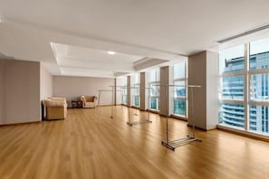 A spacious room with a wooden floor, large windows, and a standing exercise equipment. - Chuanyu Huisen Hotel (Baise)