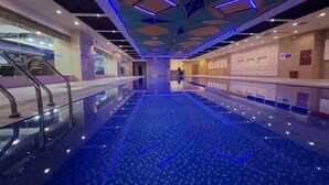 Un moderno vestíbulo de hotel con una piscina reflectante, una escalera y una zona de recepción.