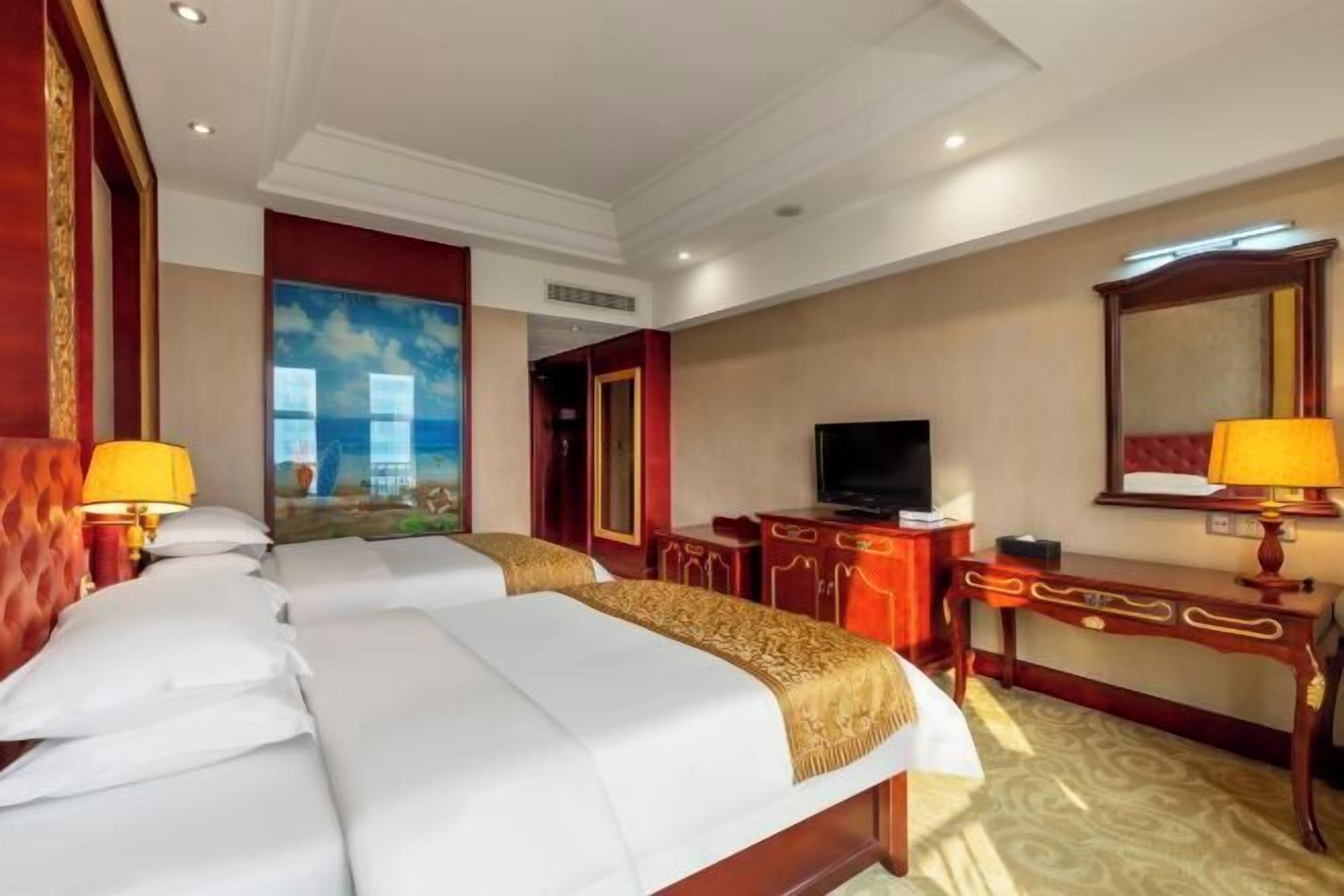A hotel room with two beds, a television, a desk, and a large window.
