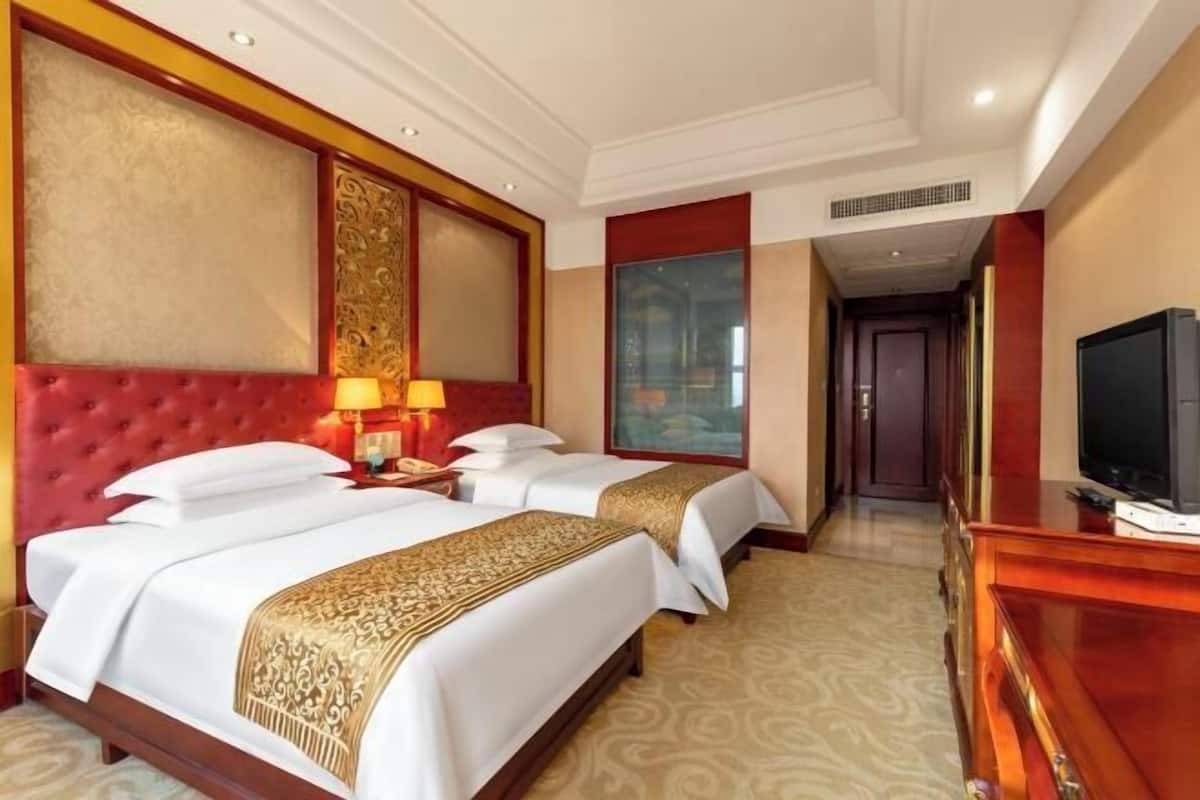 Une chambre d’hôtel avec deux lits, une télévision et une grande fenêtre.