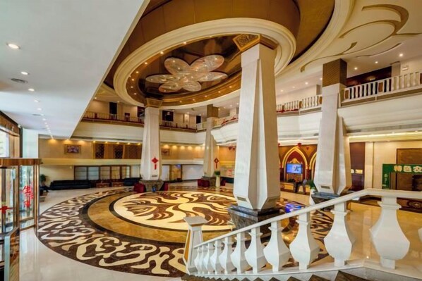 A spacious lobby with a grand staircase, multiple levels, and a decorative floor design.