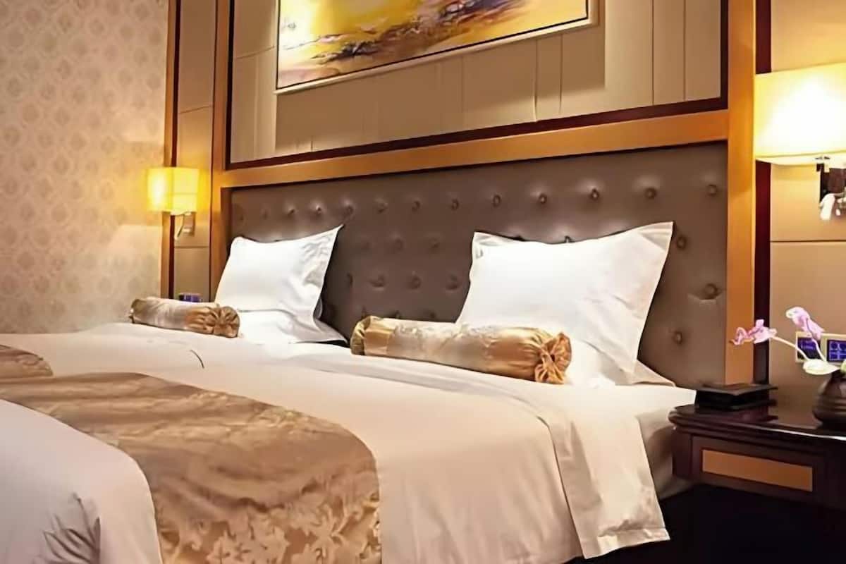 A hotel room with a large bed, two bedside tables, and a headboard with a tufted design.