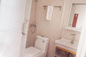 A bathroom with a toilet, a sink, and a shower. - Fuan Hotel (Jiujiang)