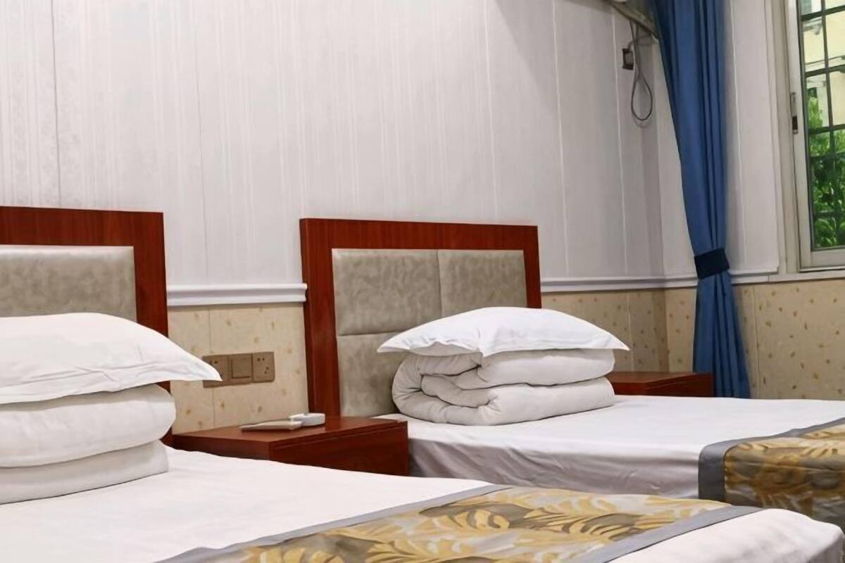 Two single beds with wooden headboards, white bedding, and a window with blue curtains.