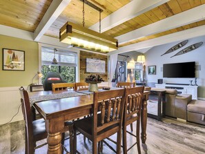 A dining area with a wooden table and chairs, a chandelier, and a large flat-screen TV mounted on the wall. - Alpine Hideaway: Cozy Ski Escape in Brian Head (Brian Head)