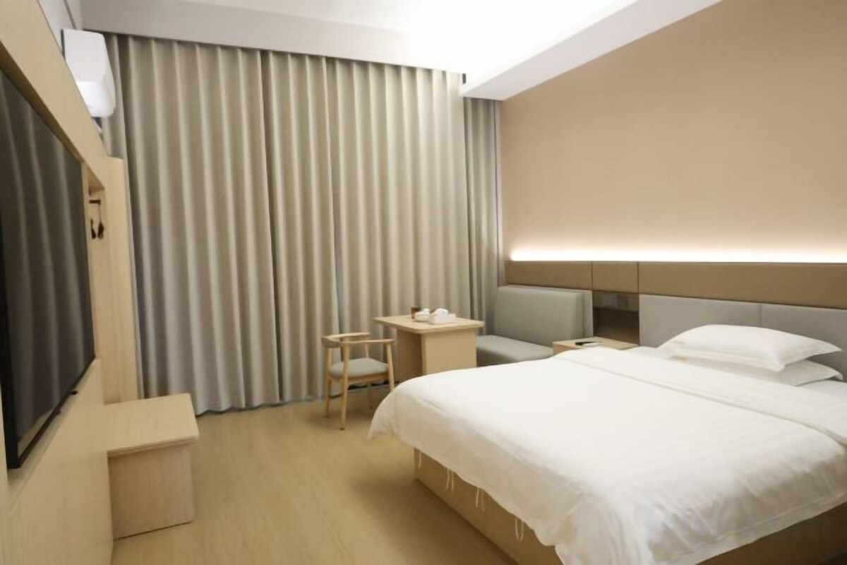 Une chambre d’hôtel avec un lit, une table de chevet, une chaise et un téléviseur.