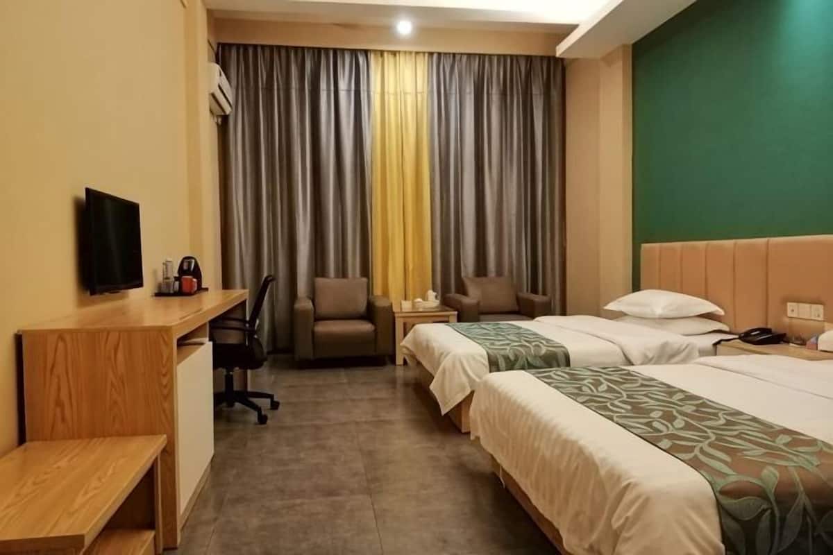 A hotel room with two beds, a desk, a chair, a television, and a window with curtains.