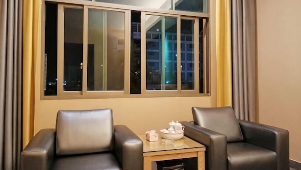 A room with two leather chairs, a small table with a bowl and teapot, and a window with curtains. - Dongshan Huatian Business Hotel (Dongshan County)