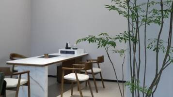 A conference room with a long table, several chairs, and a potted plant.