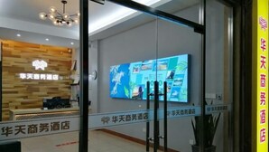 A hotel reception area with a modern design, a large digital display on the wall, and a reception desk. - Dongshan Huatian Business Hotel (Dongshan County)