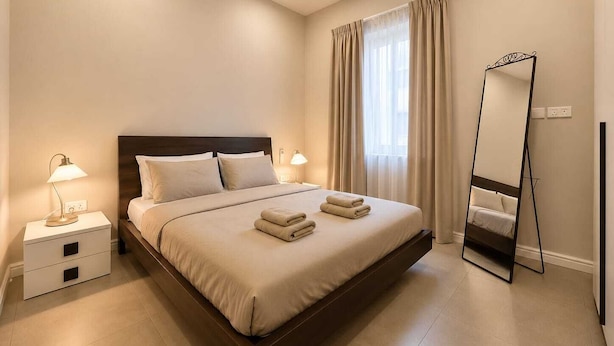 Habitación de hotel con cama, lámparas de noche, un espejo y una ventana con cortinas.