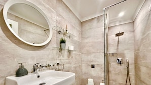 Un baño moderno con un lavamanos grande, cabina de ducha de vidrio y un espejo.