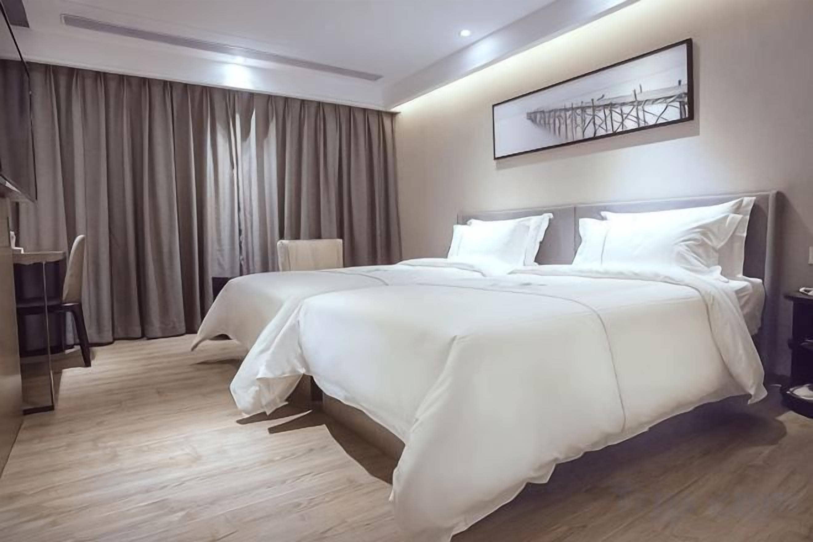 A hotel room with a large bed, a desk, and a chair.