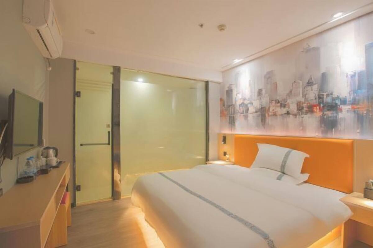 A hotel room with a bed, bedside table, and a large window.