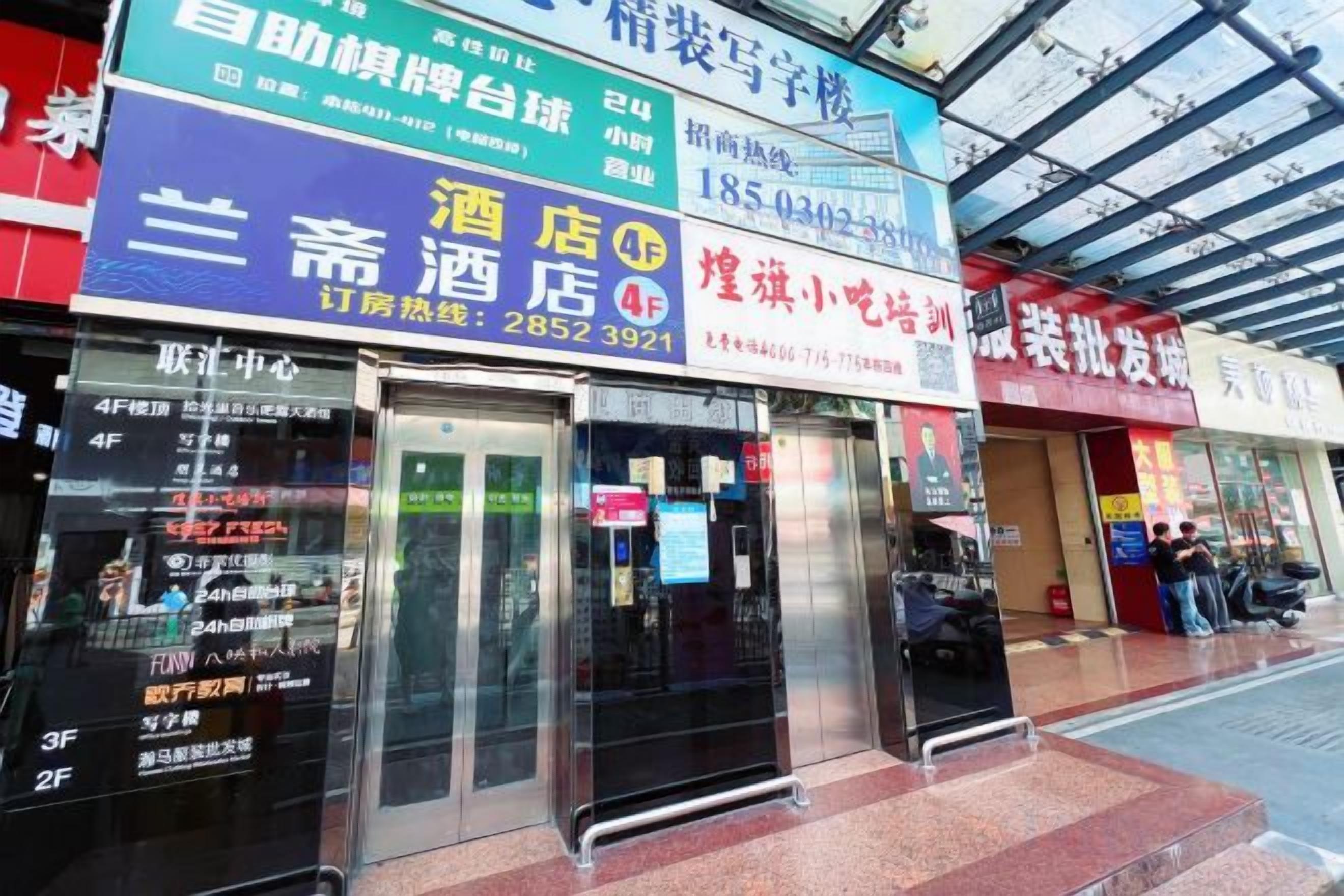 A row of storefronts with signage for a hotel, a restaurant, and a business.