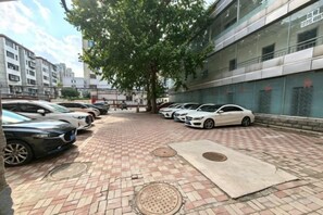 A parking area with cars, a brick pathway, and a building with large windows. - Yijia 365 Chain Hotel (Shijiazhuang Canal Bridge Railway University Yitang Metro Station Branch) (Shijiazhuang)
