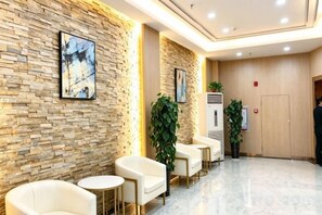 A lobby with a stone wall, seating area, and a reception desk. - Yijia 365 Chain Hotel (Shijiazhuang Canal Bridge Railway University Yitang Metro Station Branch) (Shijiazhuang)