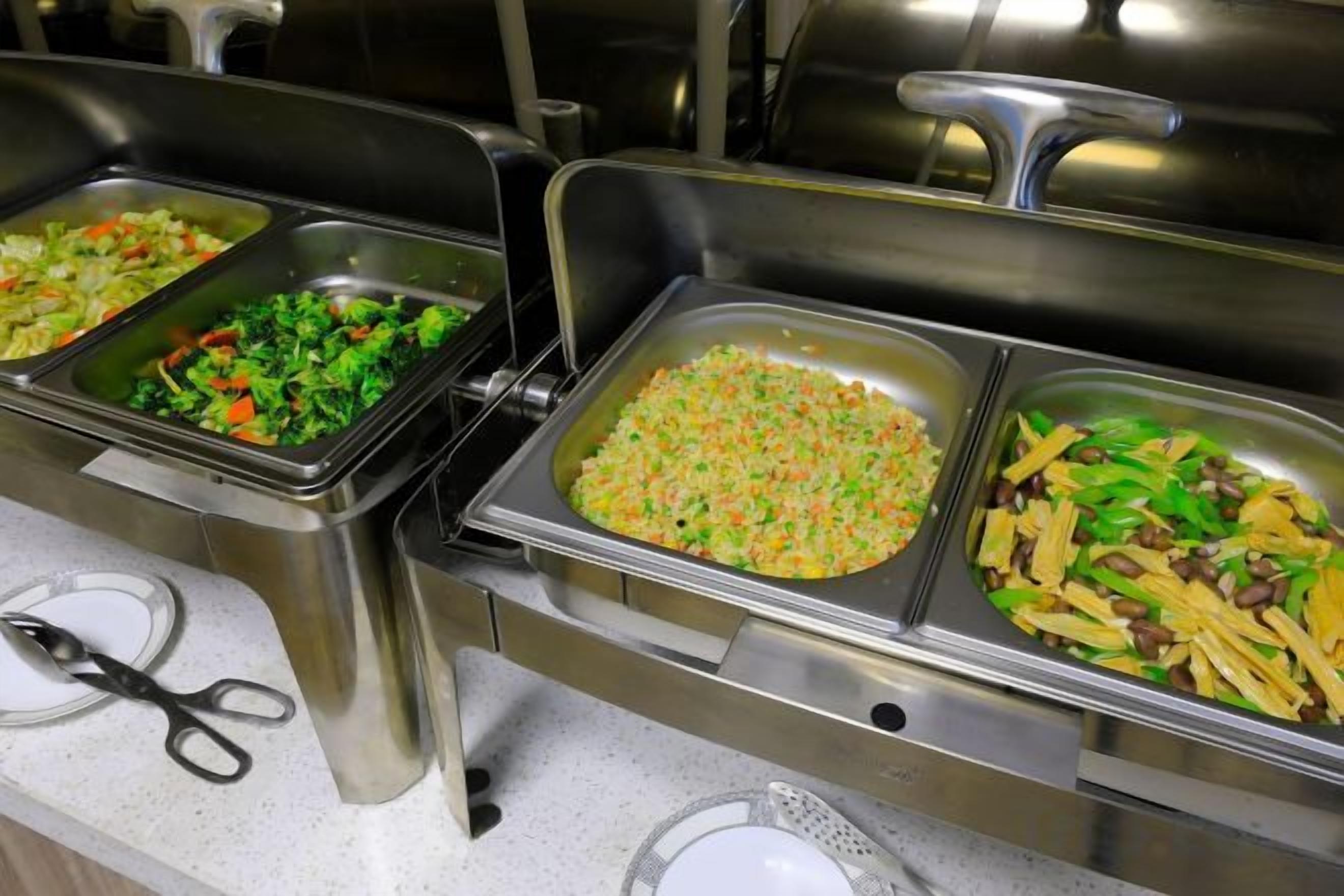A buffet with multiple food trays, including salads and rice dishes.