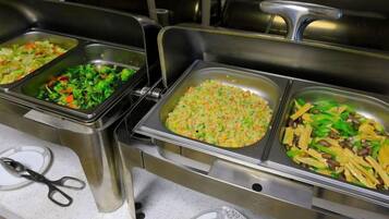 A buffet with multiple food trays, including salads and rice dishes.