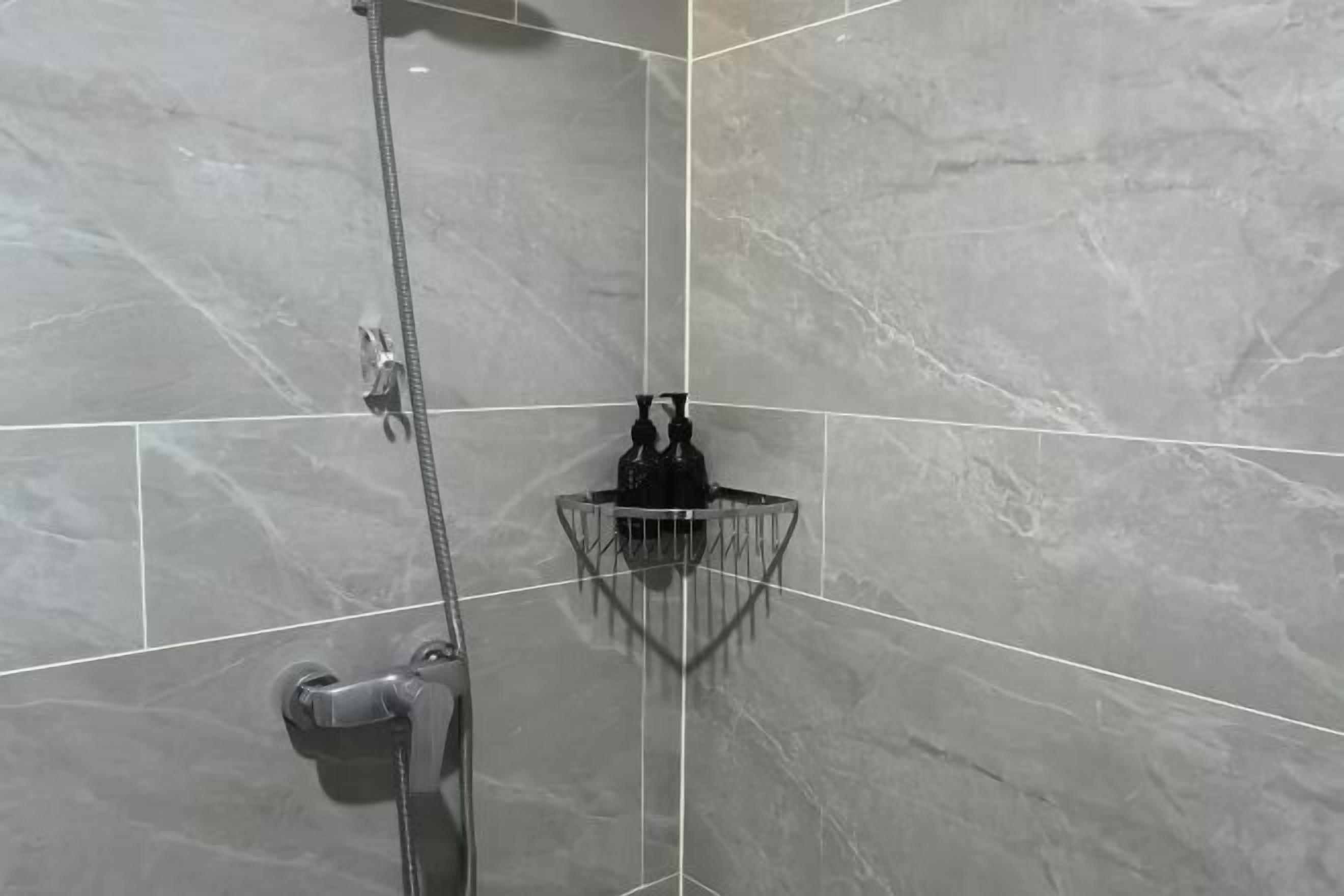 Ein Badezimmer mit Dusche, einem Handtrockner und einer kleinen Ablage für Toilettenartikel.