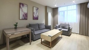 A modern living room with a sofa, a coffee table, a desk, and two abstract paintings on the wall. - Yijia 365 Chain Hotel (Shijiazhuang Canal Bridge Railway University Yitang Metro Station Branch) (Shijiazhuang)