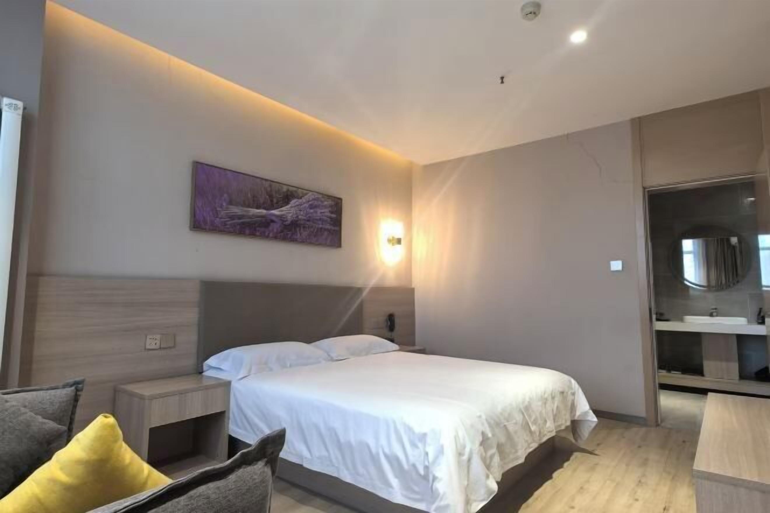 Una habitación de hotel moderna con una cama grande, mesitas de noche, una lámpara de pared y un cuadro.