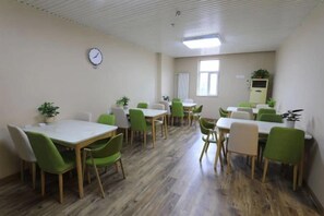 A room with multiple tables and chairs, a clock on the wall, and a window with blinds. - Yijia 365 Chain Hotel (Shijiazhuang Canal Bridge Railway University Yitang Metro Station Branch) (Shijiazhuang)