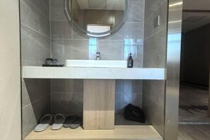 Ein Badezimmer mit integriertem Waschbecken, einem Spiegel und einem Schuhregal.