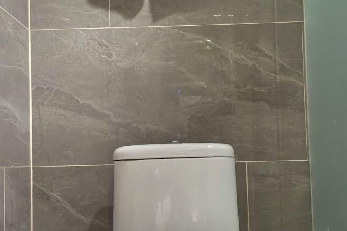 Eine Toilette in einem Badezimmer mit grauen Marmorfliesen.