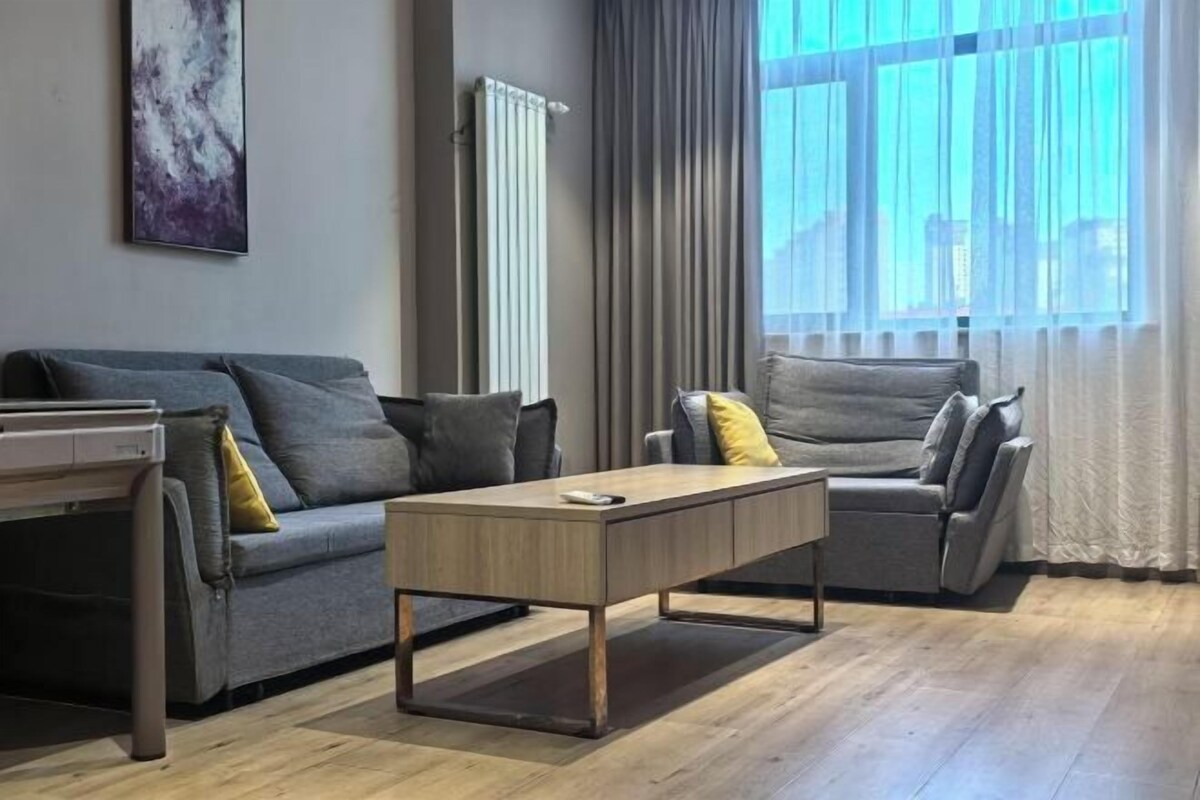 Ein modernes Wohnzimmer mit grauem Sofa, einem Holztisch und einem grauen Sessel.