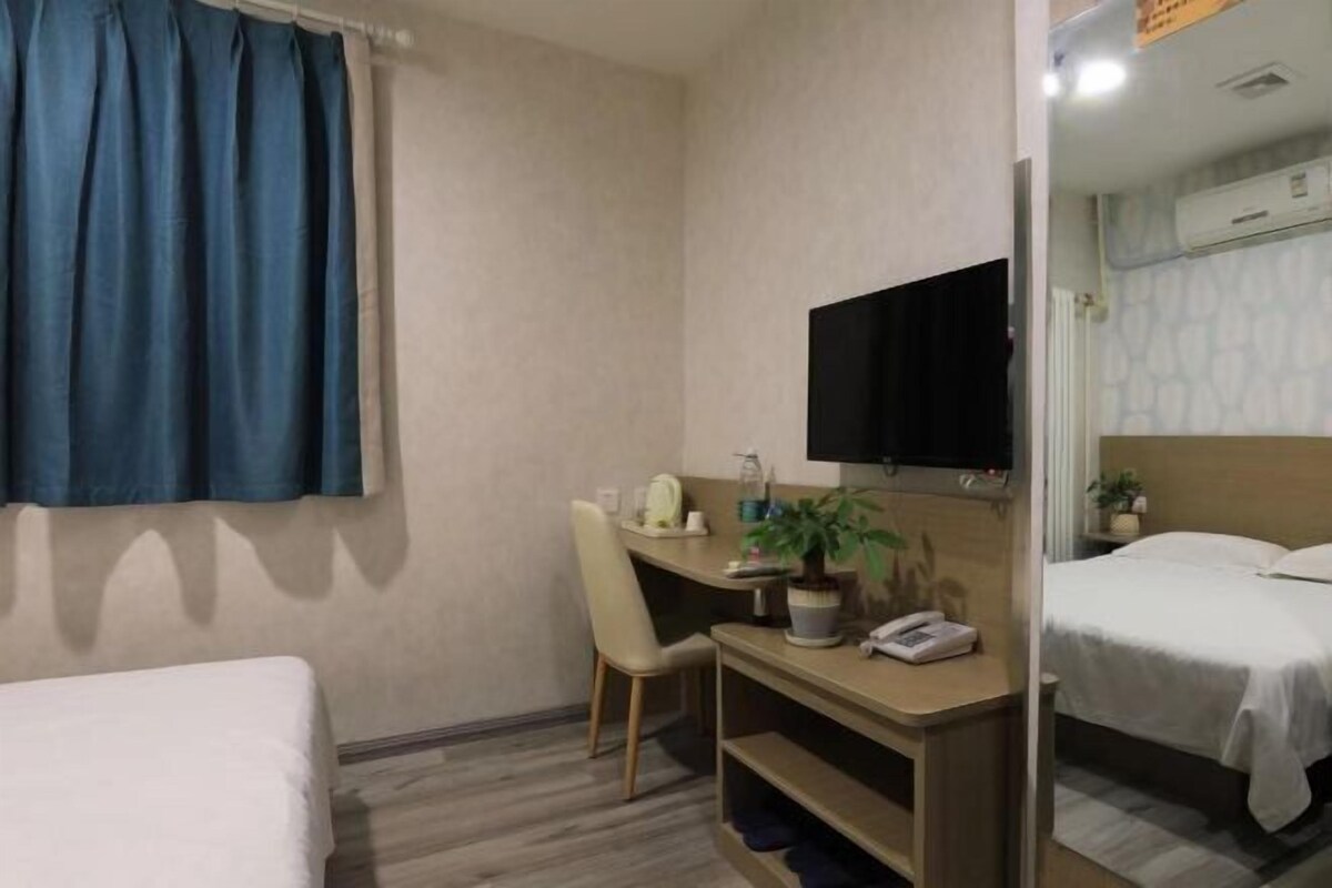Ein Hotelzimmer mit einem Bett, einem Schreibtisch mit Stuhl, einem Fernseher und einer Topfpflanze.