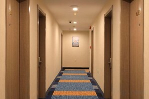 Ein Hotel-Flur mit Holztüren, einem gemusterten Teppich und einem gerahmten Bild an der Wand.