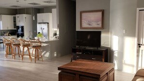 Una sala de estar moderna con una mesa de centro de madera, un televisor y un comedor con sillas de mimbre.