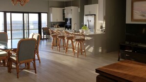 Una cocina amplia con electrodomésticos modernos, un comedor con sillas de mimbre y un ventanal con vistas.
