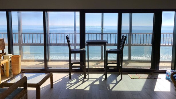 Un balcón con vista al mar, amueblado con dos sillas y una mesita.