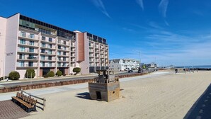 Un hotel frente al mar con varios balcones, una playa arenosa y un cielo azul despejado.
