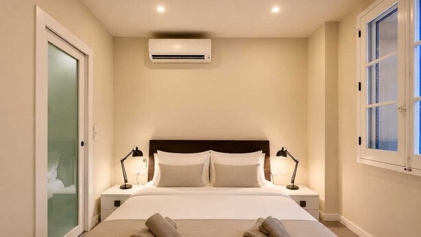 Ein Hotelzimmer mit einem Bett, zwei Nachttischlampen, einer Klimaanlage und einem Fenster.