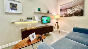 Ein modernes Wohnzimmer mit Flachbildfernseher, Couchtisch, Sofa und Lampe.