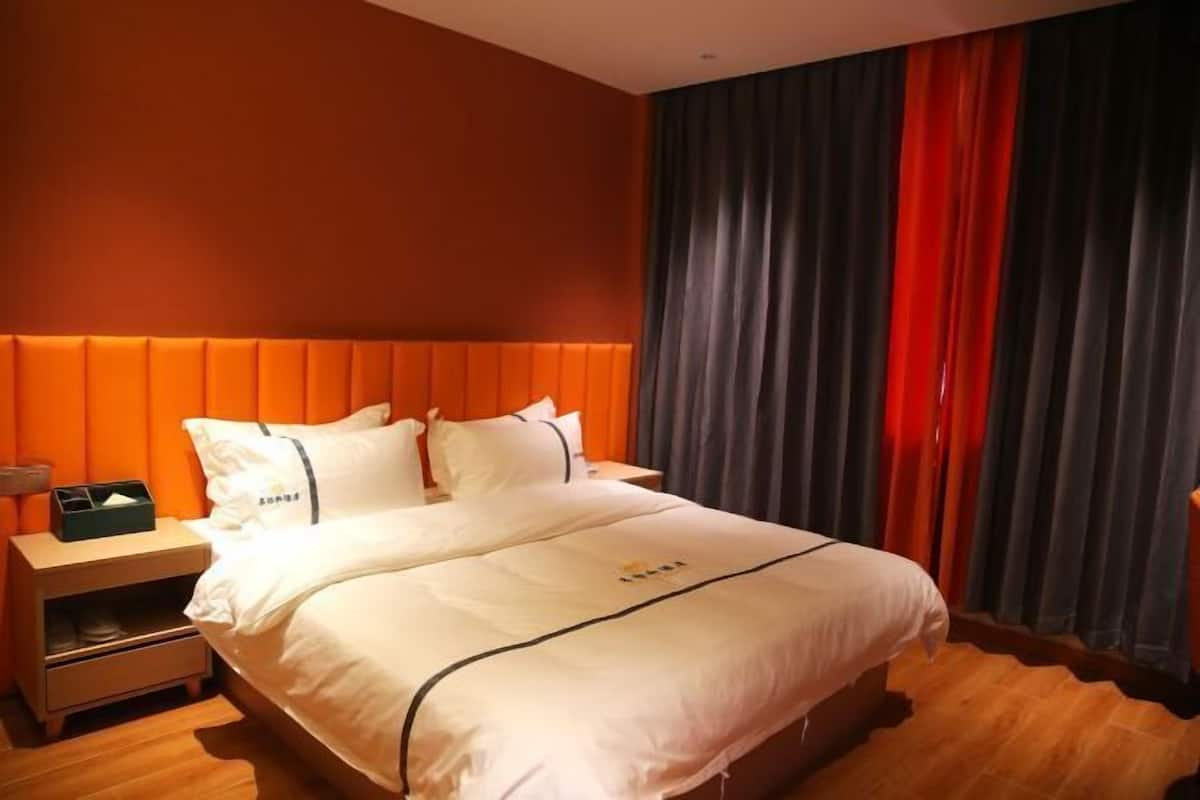Ein Hotelzimmer mit einem großen Bett, einem Nachttisch und einem fensterbepflanzten Fenster.