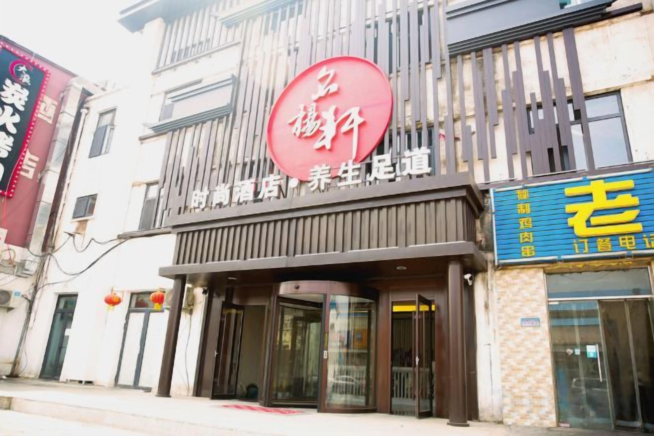 A building with a prominent red sign, a storefront with a blue sign, and a traditional architectural style.