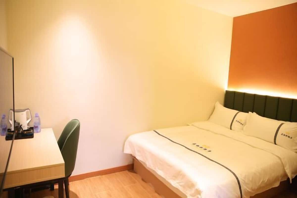 Ein Hotelzimmer mit Bett, Schreibtisch mit Stuhl und Wandlampe.