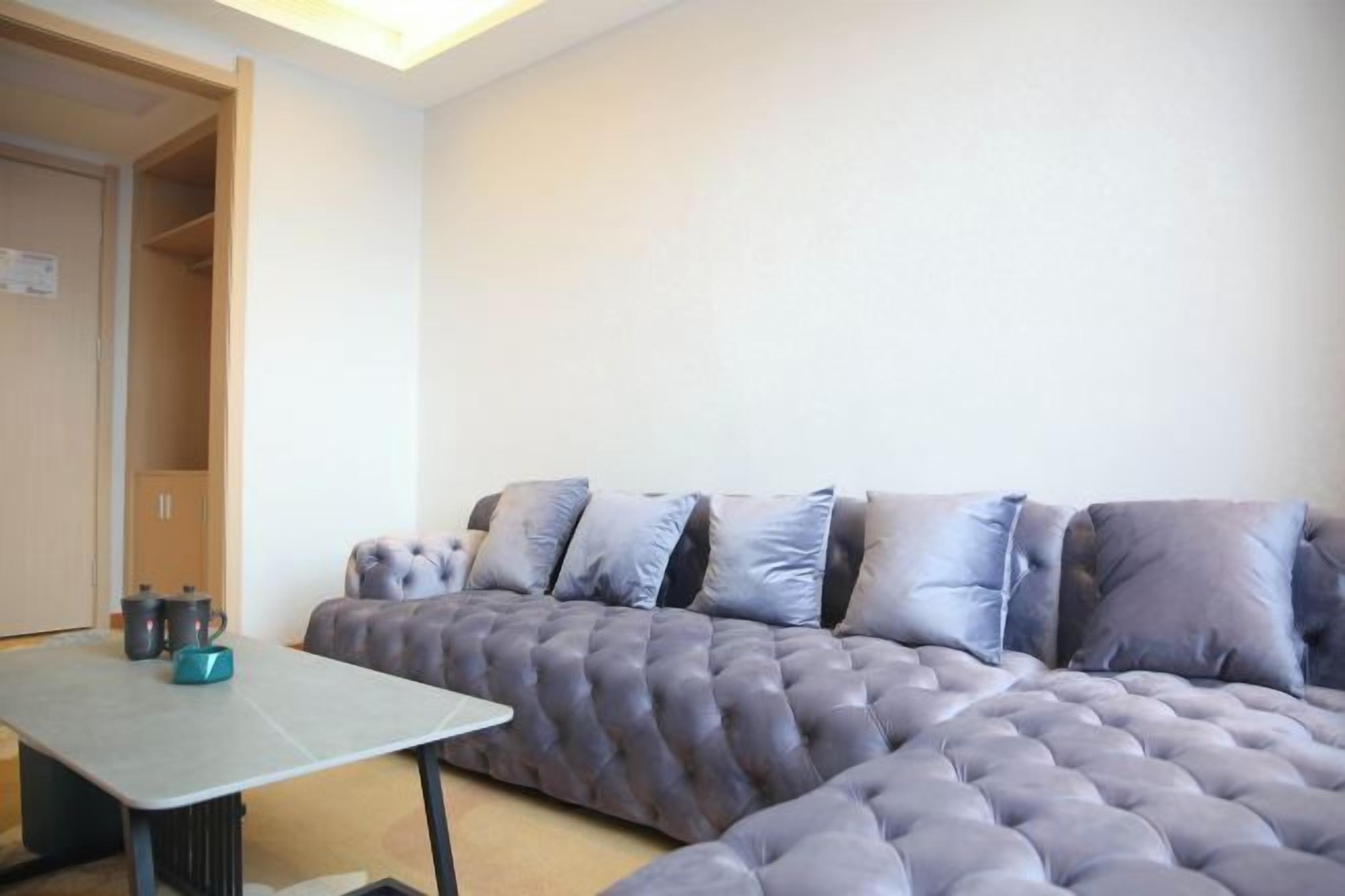 A modern living room with a sectional sofa, a small table, and a door leading to another room.