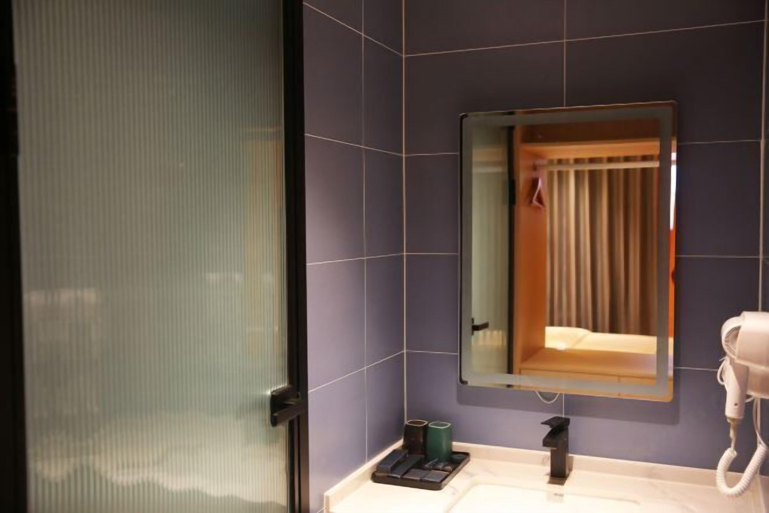 Un baño con espejo, secador de pelo y lavabo.